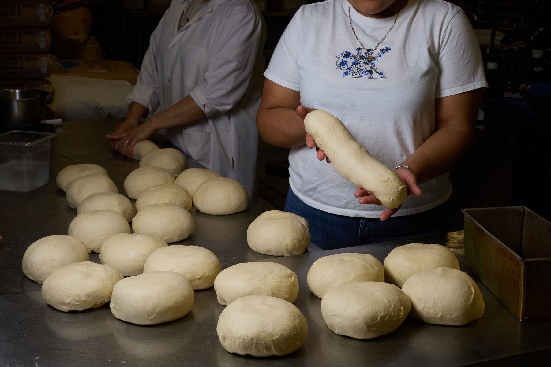 Bakers shaping dough by hand on stainless steel table